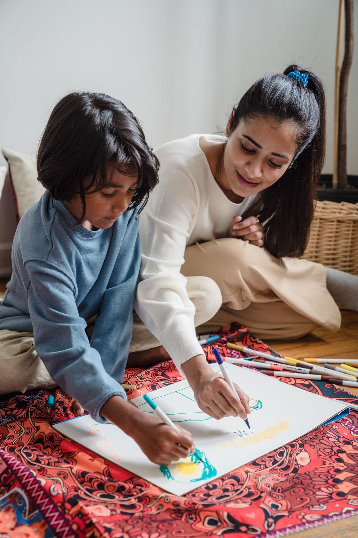 An Indian mother and her child drawing a colourful picture together at home
